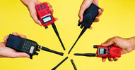 Six hands hold handheld red and black two-way radios in an alternating color pattern in a circle.